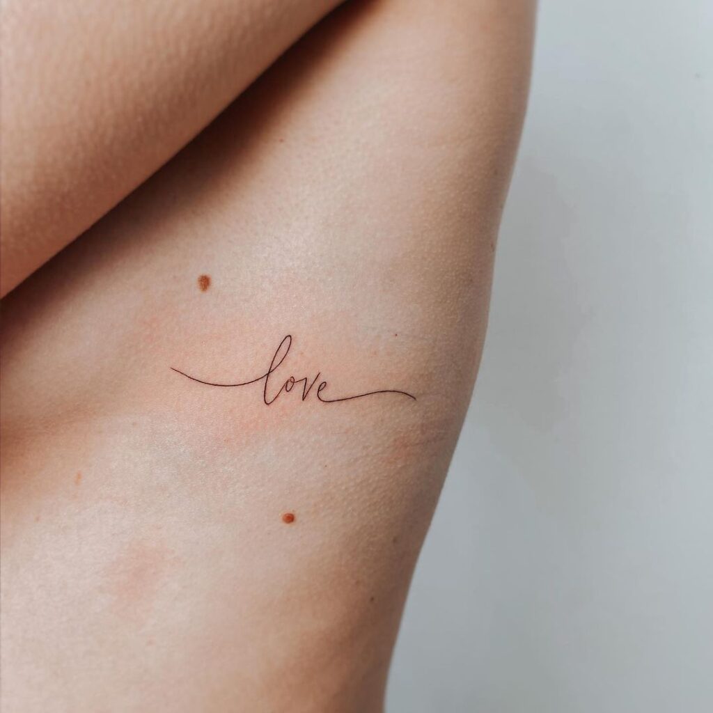 Een tattoo van "liefde" op de ribbenkast