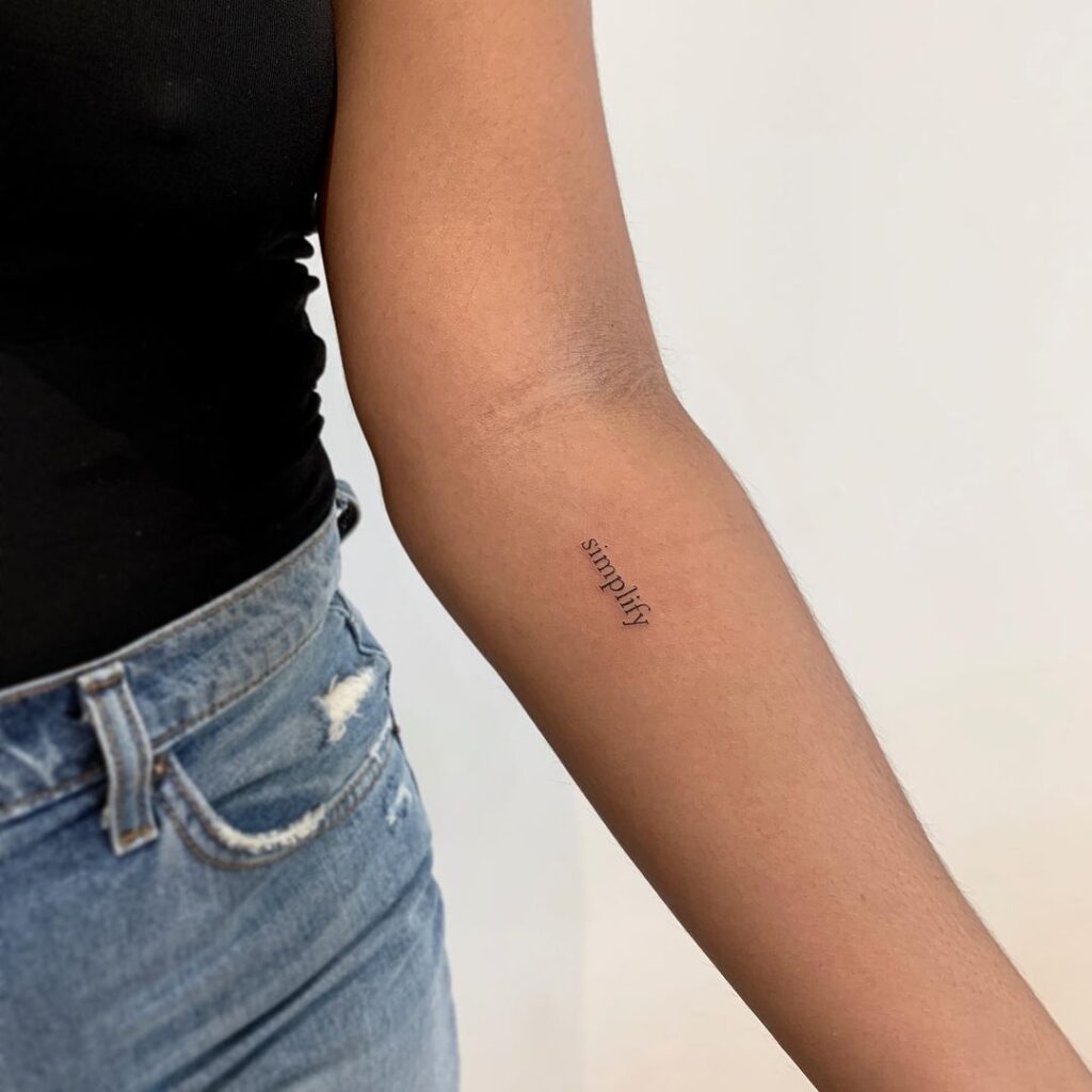 Een "simplify" tattoo op de onderarm