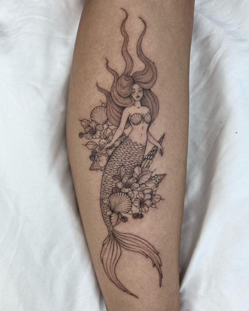 1. Een tattoo van een zeemeermin met bloemen en schelpen 