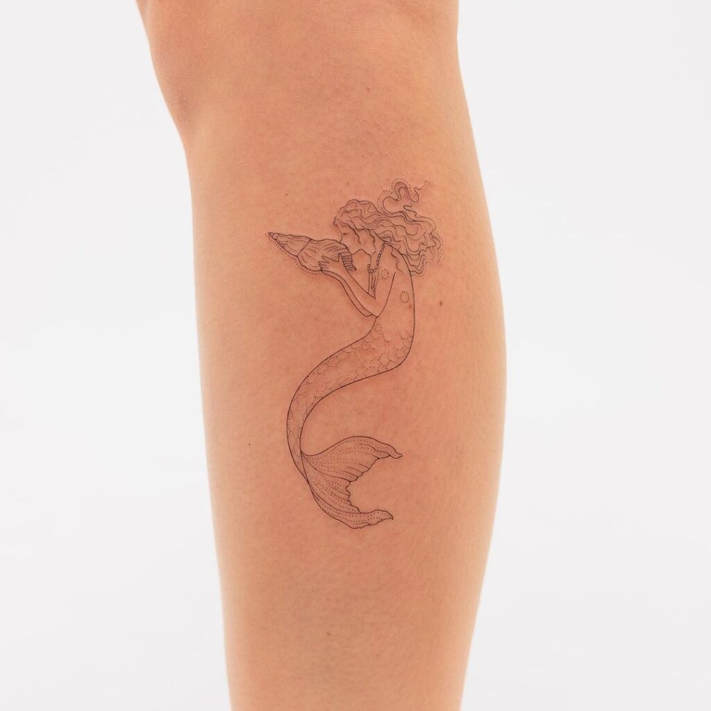 11. Een tattoo van een zeemeermin die een zeeschelp kust 
